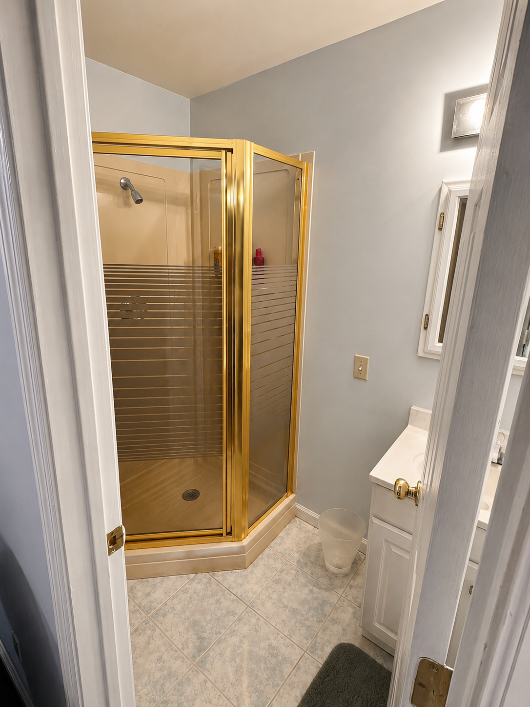 Dated bathroom with gold-framed shower before remodel